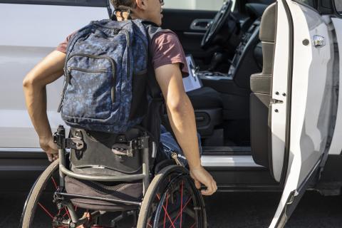 Un étudiant en fauteuil roulant monte à bord d'une voiture.