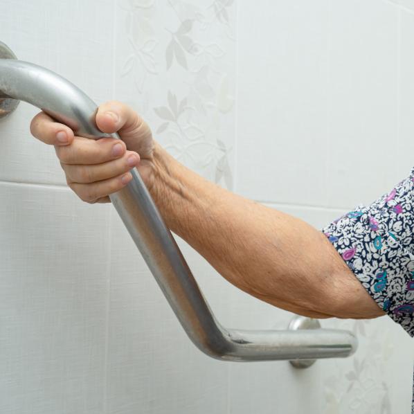 Une personne âgée s'accroche sur une rampe pour prendre la douche