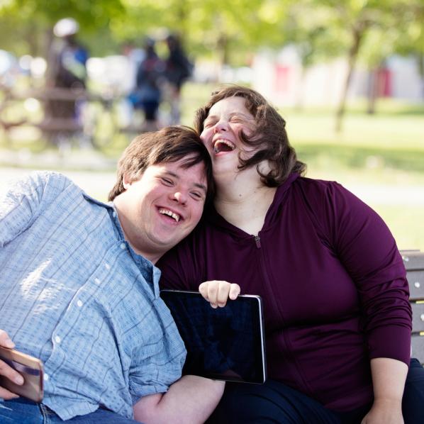 Deux jeunes adultes ayant une déficience intellectuelle en plein fou rire dans un parc
