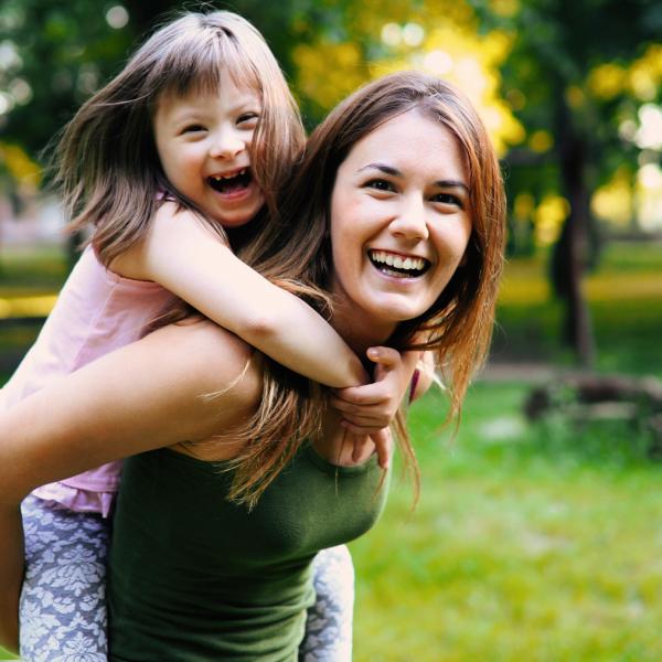Une femme porte sa fille sur son dos et rigolent ensemble