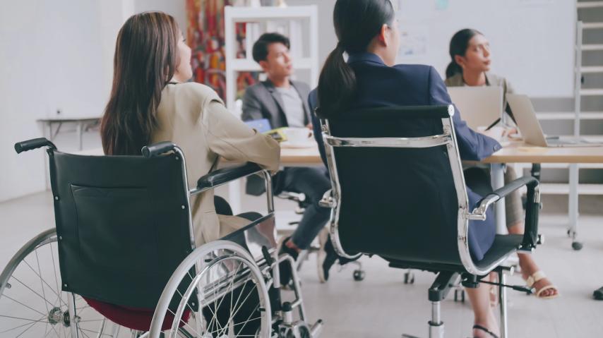 Personne en fauteuil roulant en réunion de travail avec des collègues.
