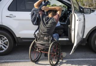 Un enfant en situation de handicap moteur met son sac à dos pour aller en classe